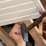 man hands driving nail with hammer, building works