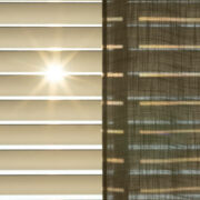 The sun shining through blinds, shades and a curtain. With a blue sky during springtime.