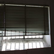windows, backlight by morning sun, shutter half open, shadows grills created by the external light.