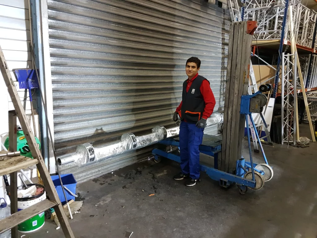 Technicien FMF effectuant la préparation et la maintenance d’un rideau métallique dans un atelier