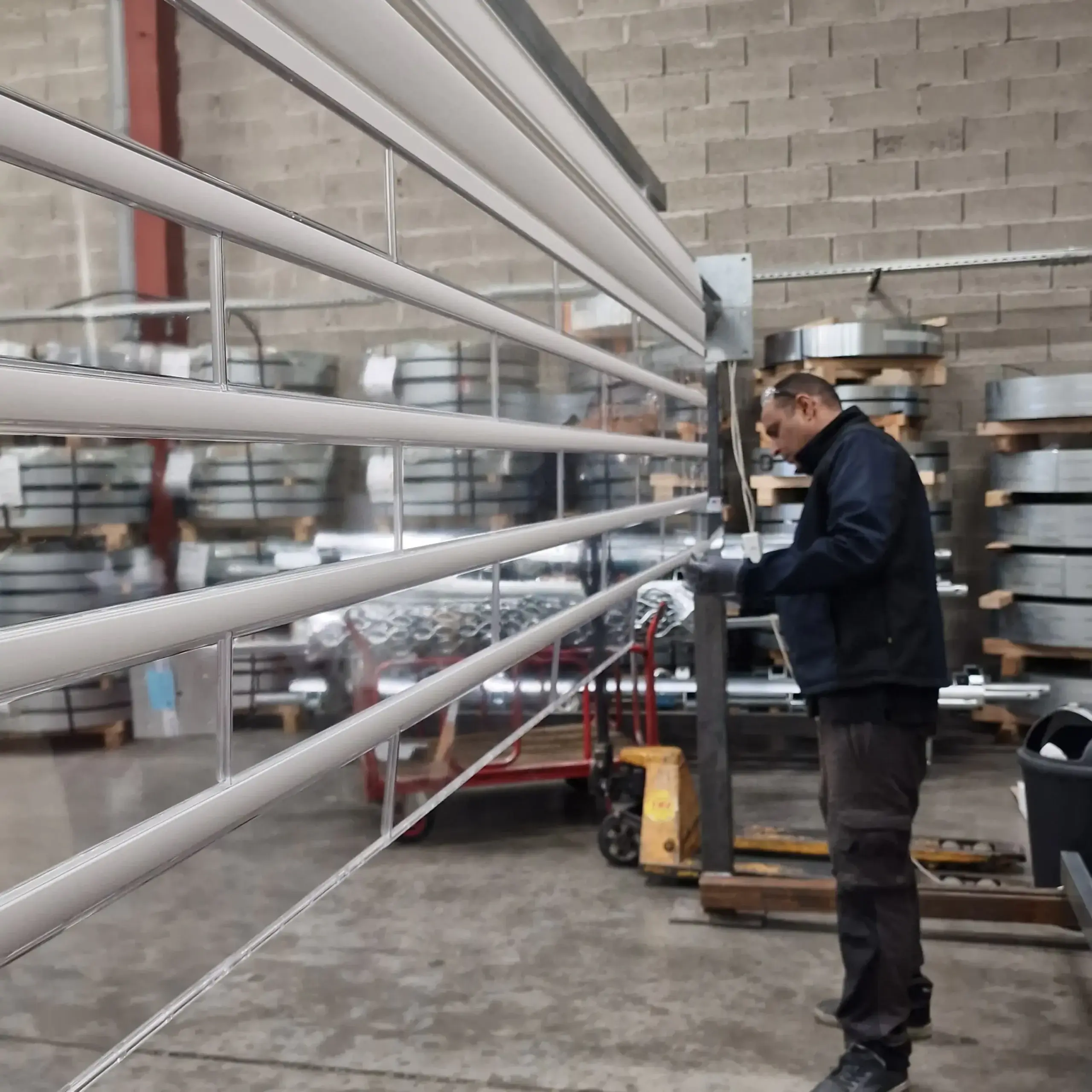 Technicien fabriquant un rideau métallique transparent en atelier